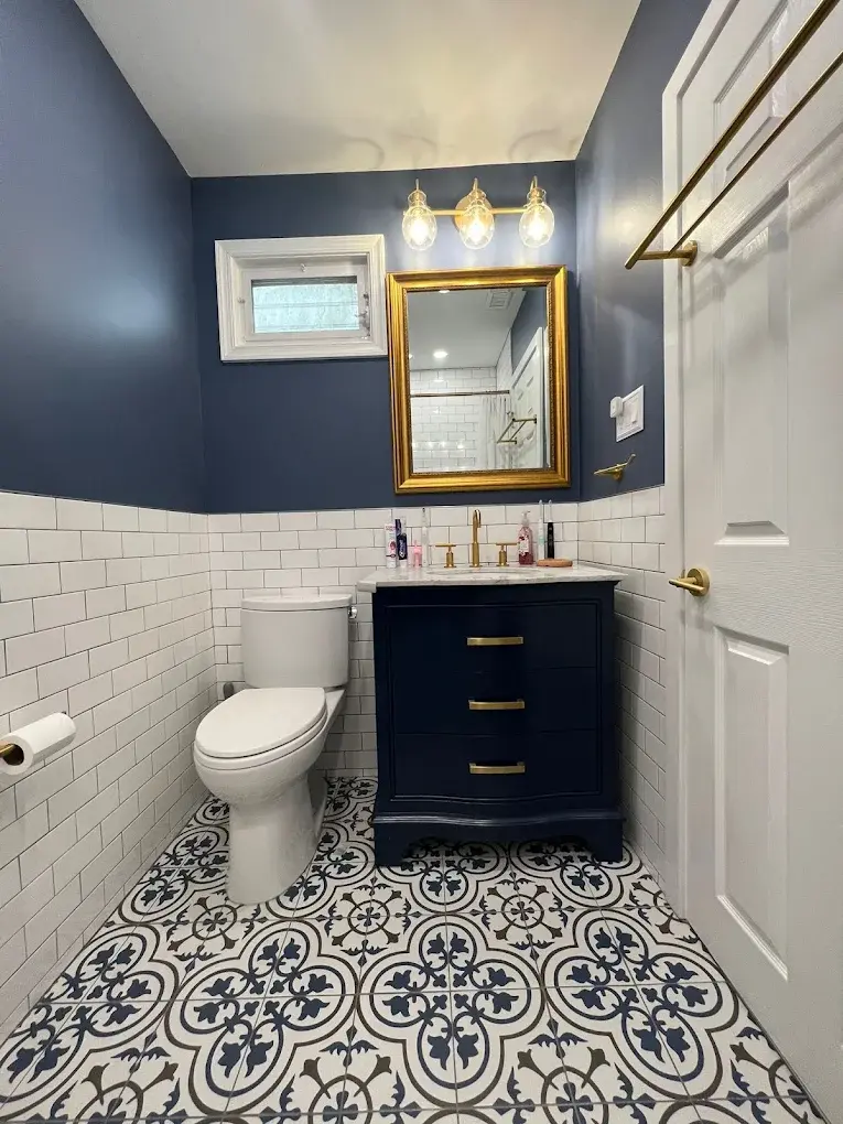 Modern navy bathroom remodel with patterned tile floor and gold fixtures